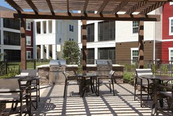 a patio with tables and chairs and a grill